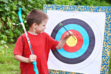 Little archer with bow pull out arrow from aim outdoors