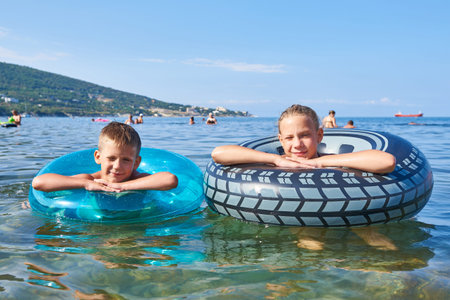 Happy boy and girl swimming with toy lifebuoys