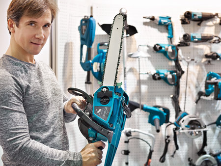 Man chooses a gasoline chain saw in store