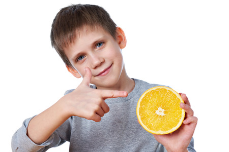 Happy child with an orange isolated on white backgroundの写真素材