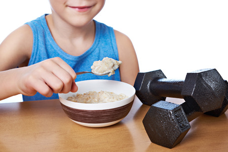 Boy eating porridge and dumbbells as symbols of sports lifestyleの写真素材