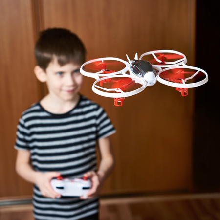Little boy drives toy quadcopter drone at homeの写真素材