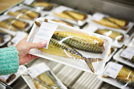 Buyer chooses smoked fish mackerel in supermarketの写真素材