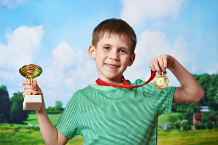 Boy sportsman winner with cup and medal on nature backgroundの写真素材