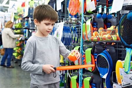 Boy with a racket and a ball for beach tennis in a sports shopの写真素材