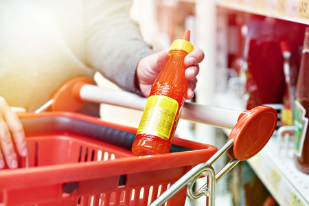 Hot chilli sauce in the hands of the buyer at the grocery storeの写真素材