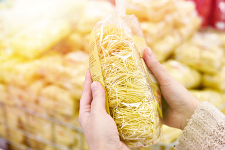 Pack of spaghetti in the hands of the buyer at the storeの写真素材