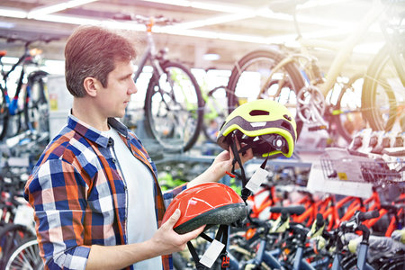 Man chooses helmet for cycling before buying in sports shop