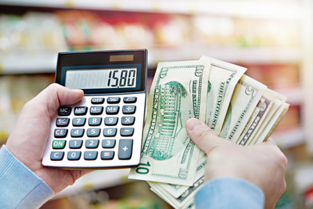 Man with dollars and calculator considers costs in the storeの写真素材
