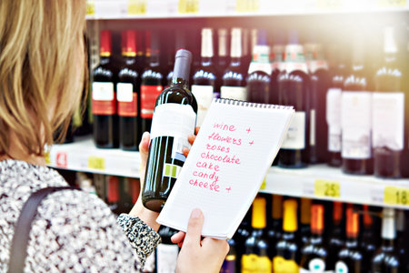 Girl chooses bottle of wine for date in the storeの写真素材