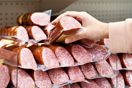 Smoked sausage in the hands of the buyer in the storeの写真素材