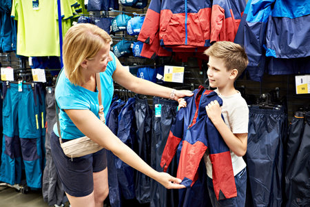 Boy with mom choosing jacket in the store