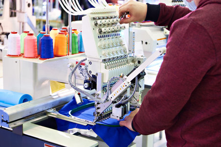 Working technician specialist embroidery industrial machine in sewing workshop