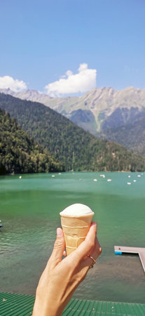 Hand with ice cream and lake Ritsa in abkhaziaの写真素材