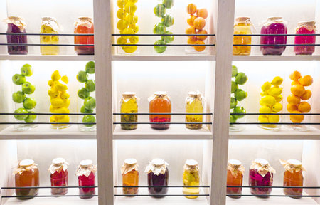 Glass jars with fruits on decorative wallの写真素材