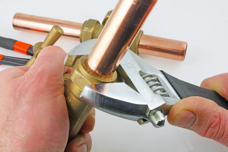 New copper pipework being constructed   A plumber with an adjustable wrench tightening up compression fitting against a grey backgroundの写真素材