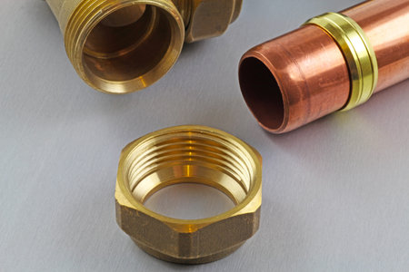 Plumbing â€“ A close up view  of a compression fitting on a grey background.
