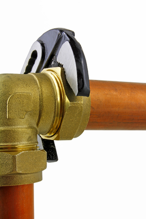 Plumber's adjustable wrench tightening up  copper pipework â An adjustable wrench tightening up a compression tee to 15mm copper pipework  on a white  backgroundの写真素材