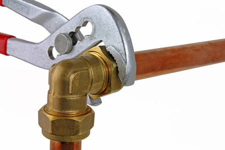 Plumber's adjustable wrench tightening up  copper pipework â An adjustable wrench tightening up a compression elbow to 15mm copper pipework  on a white  backgroundの写真素材