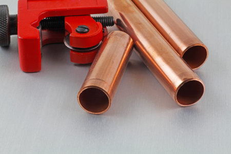 New copper pipework ready for construction â Adjustable wrench, 15mm copper piping and brass joints laid together against a grey backgroundの写真素材