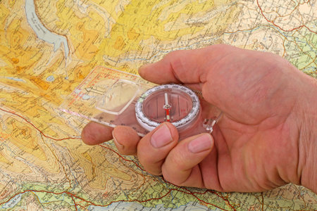 Compass and  map -  A hand holding a magnetic compass being lined up to walk on a magnetic bearing