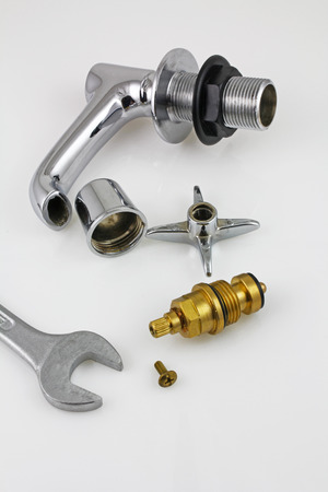 Sink tap repair â A stripped down sink tap and spanner laying on a grey backgroundの写真素材
