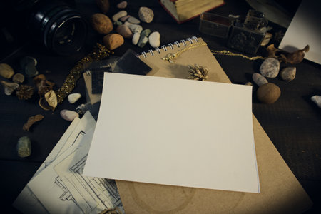 Composition of old objects reminiscent of traveling On a wooden table there is an old camera, a book, old papers, a roll of paper tied with a string, a seashell and pebbles from the seashoreの写真素材