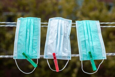Multi-colored surgical masks hanging on a clothesline with colored clips.Concept of reuse of medical masks or N95 masksの写真素材