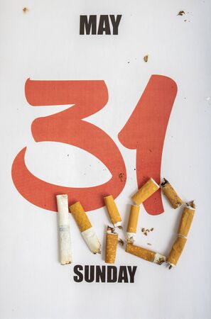 Concept image for World No Tobacco Day. Broken and burnt cigarettes lying on a calendar with the day May 31の写真素材