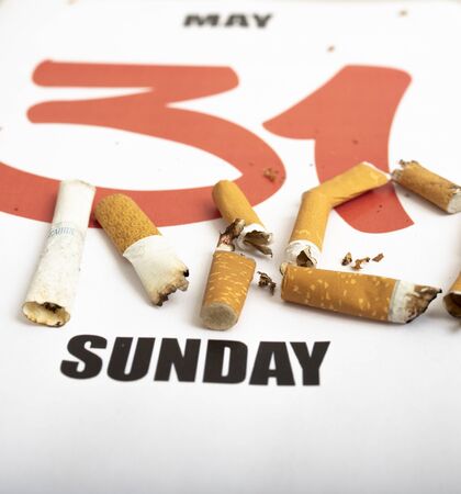 Concept image for World No Tobacco Day. Broken and burnt cigarettes lying on a calendar with the day May 31の写真素材
