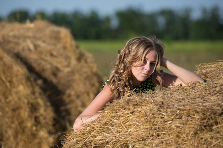 Pretty young girl on a haystack