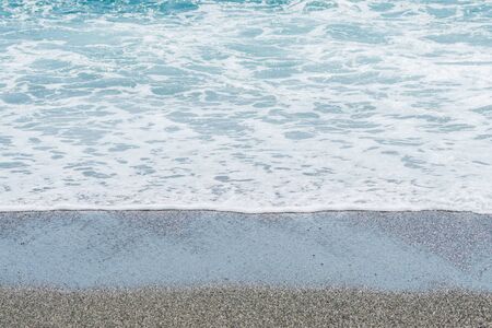 The tide coming in on a beach with wet sand.の写真素材