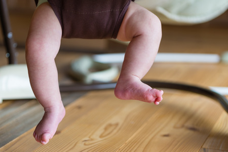 The feet and legs of a baby playing in a jumper.の写真素材