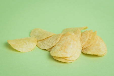 A macro shot of mini potato chips on a green background.の写真素材