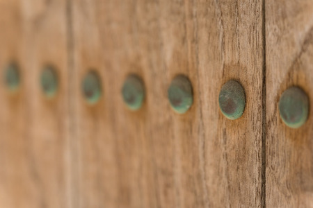 A macro shot of old copper nails which haved turned green due to oxidation on an old wooden door.の写真素材