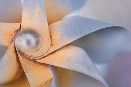 A macro shot of a decorative pinwheel garden ornament made of rusted metal.の写真素材