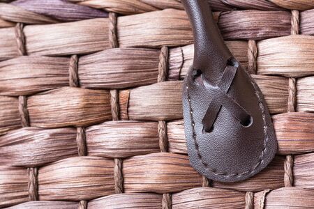 A macro shot of a leather handle stitched into a brown wovel wicker basket.の写真素材