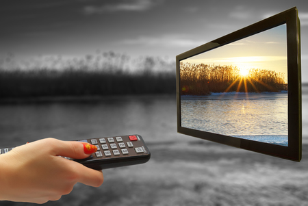 girl hand switches TV channels. Nature. Abstract. remote control in hand and TVの写真素材