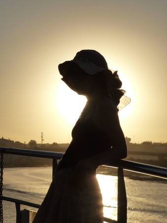 silohuette girl with hat in the sunsetの写真素材