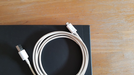 Charging cord and the laptop on the wooden table.の写真素材