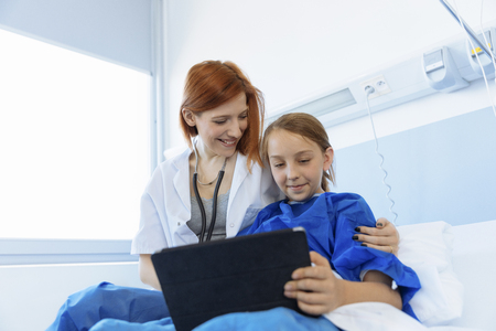 Doctor showing digital tablet to Girl patientの写真素材