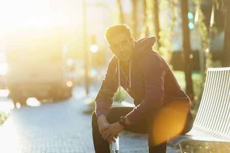 Athlete resting on the bench with bottle of waterの写真素材