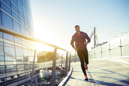 athlete with earphones running in the cityの写真素材