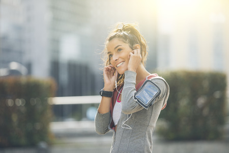 Beautiful young woman runner athlete insert her earphones during trainingの写真素材
