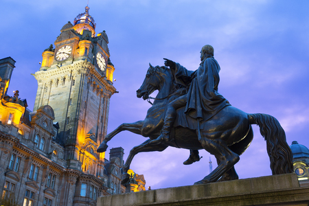 Statue of Wellington on horseback silhouetted against a blue sky, with the clock tower of Balmoral Hotel in the backgroundのeditorial素材