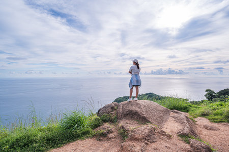 Young woman standing on top of the mountain and looking at the sea