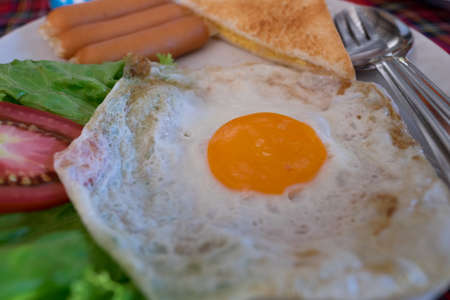 Breakfast with fried egg, sausages, toast and vegetable.