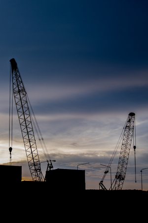 Crane transport container docks area silhouette with sunset backgroundの写真素材