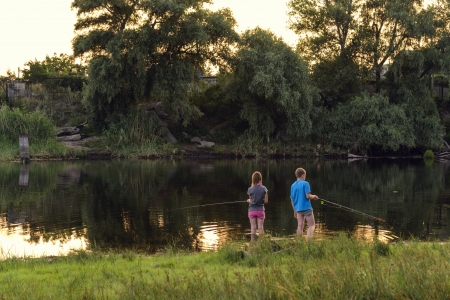 Boy and girl fishing on a lakeの写真素材