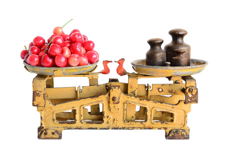 Sweet cherries on the old fashioned scales with kettlebells. Isolated on white backgroundの写真素材